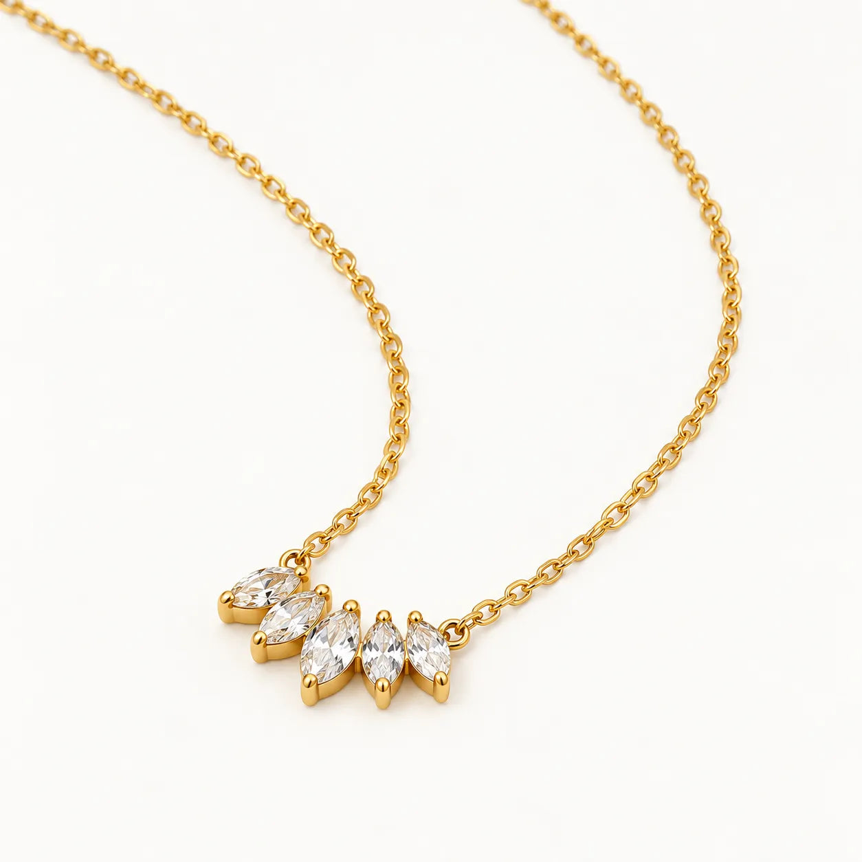A delicate gold chain necklace featuring a small cluster of four marquise-cut clear gemstones in a gold setting, displayed on a clean white background.